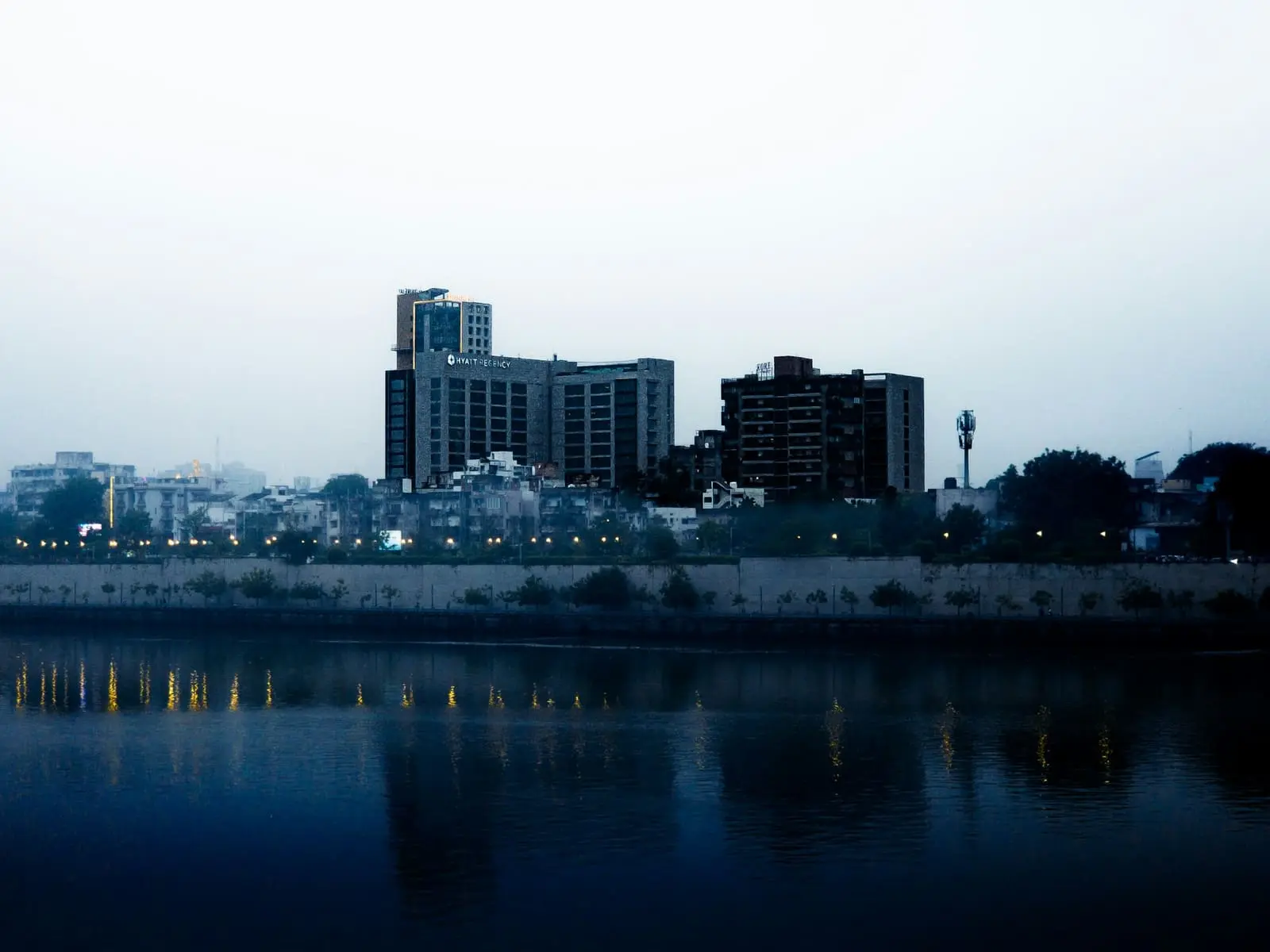 The Sabarmati riverfront in Ahmedabad at dusk with buildings lit along the bank
