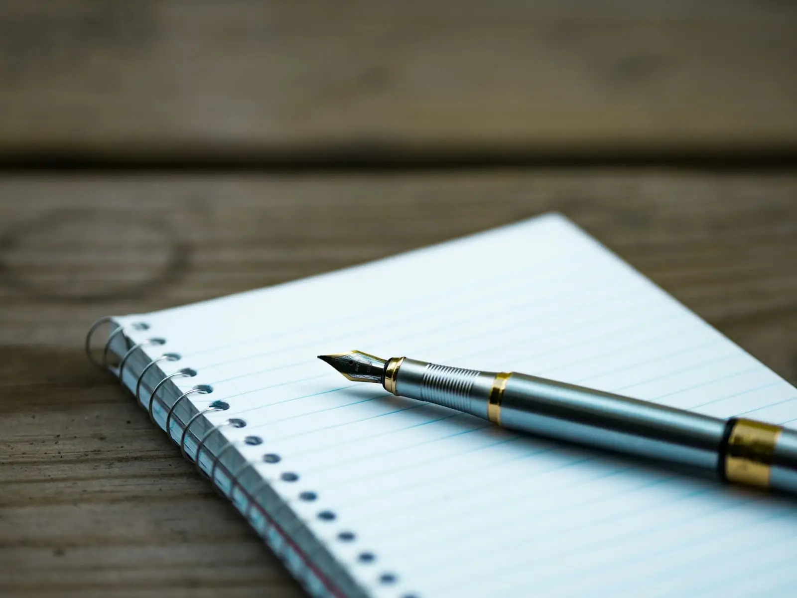 A fountain pen resting on an open spiral notebook