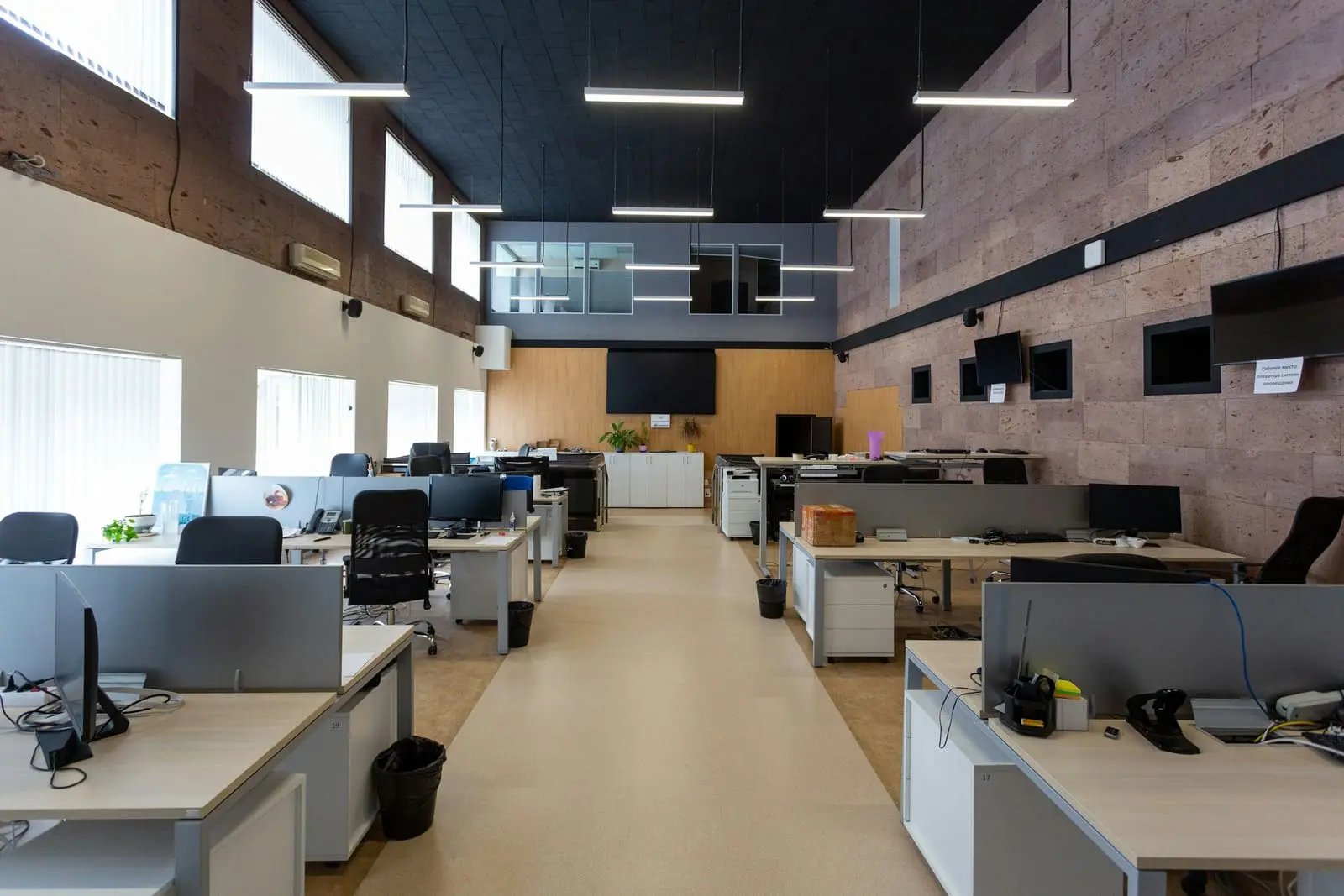 An open-plan office with rows of desks under linear lights