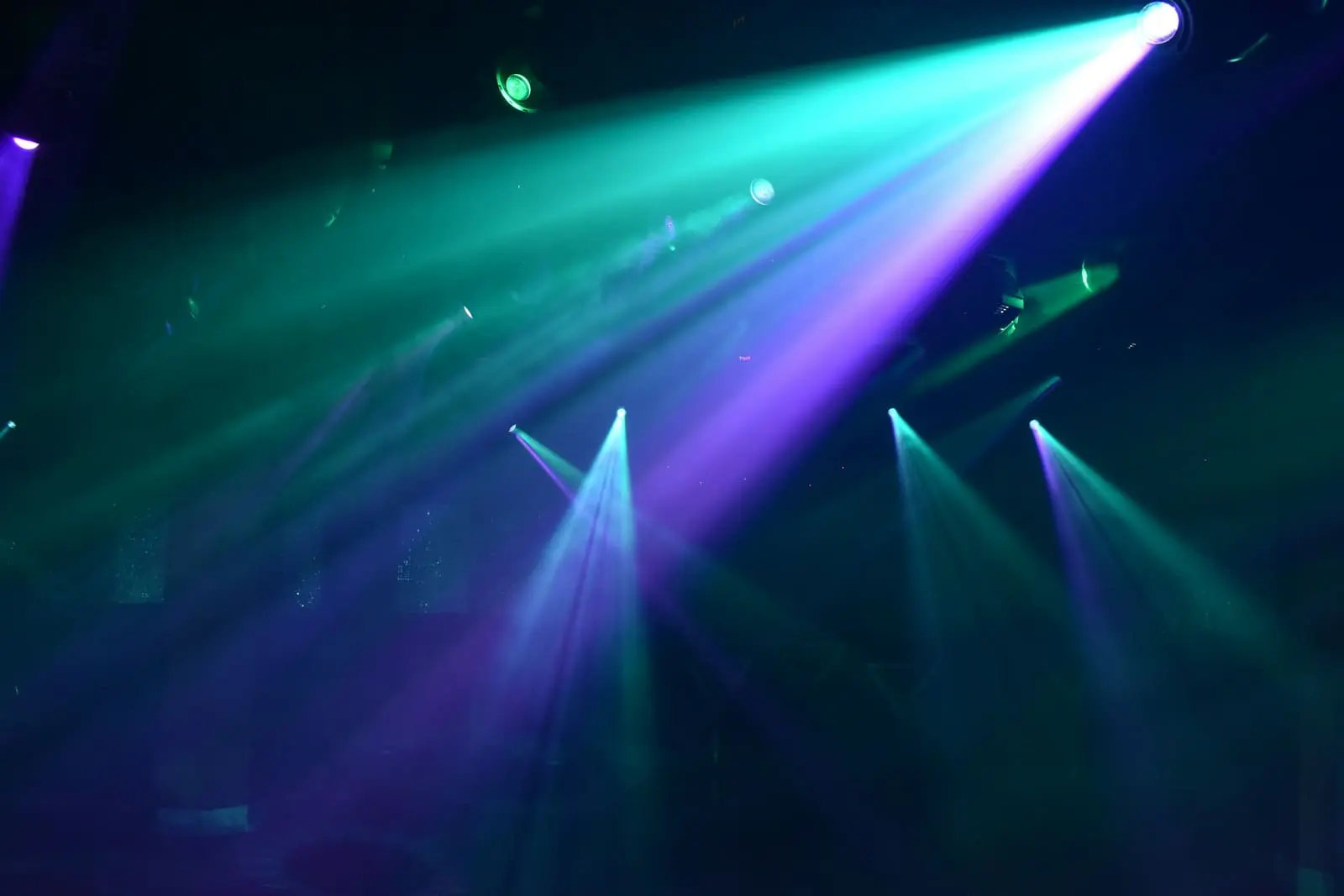 Teal and purple stage spotlights cutting through haze at an event