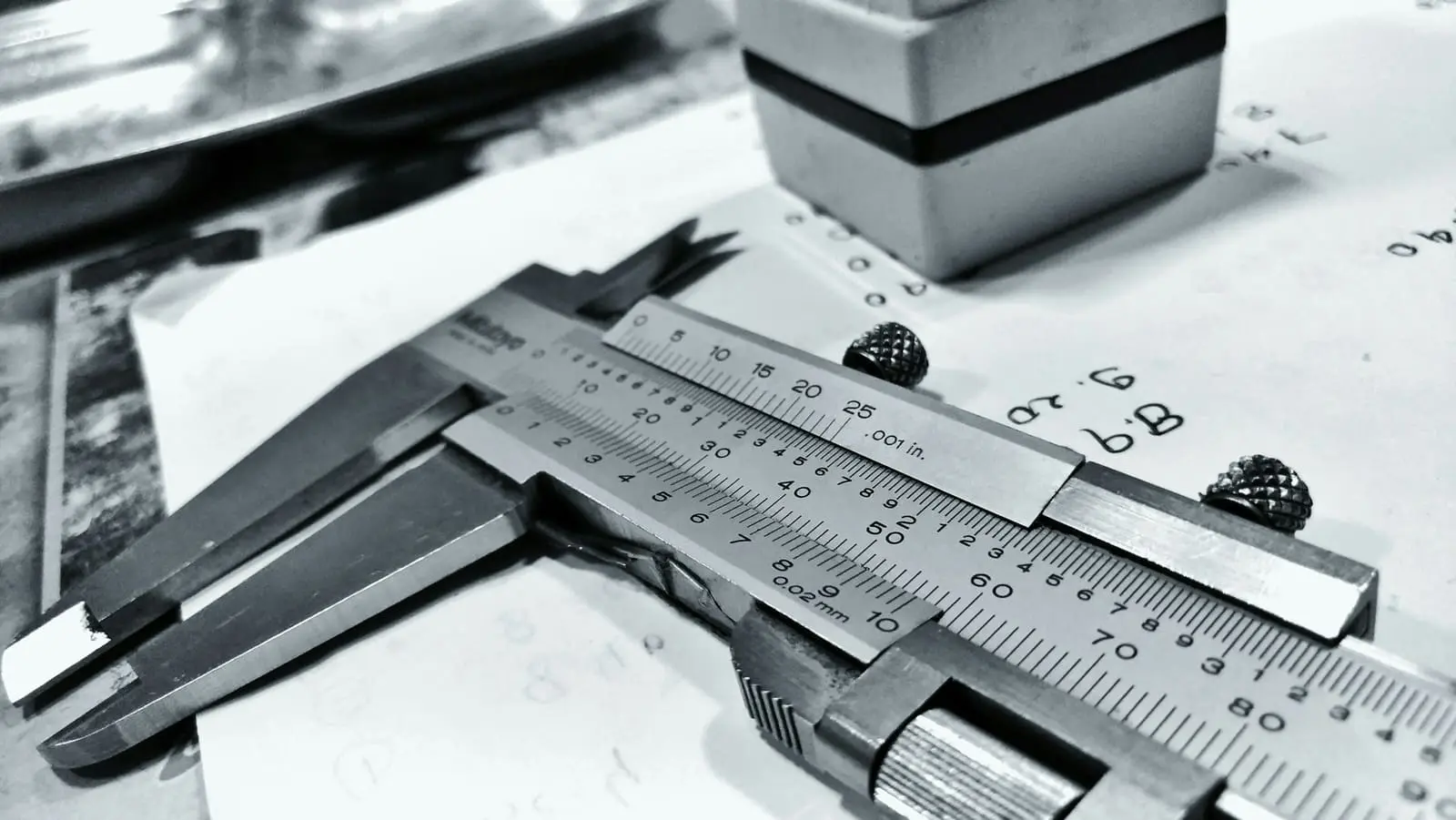 A dial caliper and steel rule laid on technical drawings
